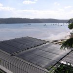 Heliocol solar pool heating panels installed on a roof by the water
