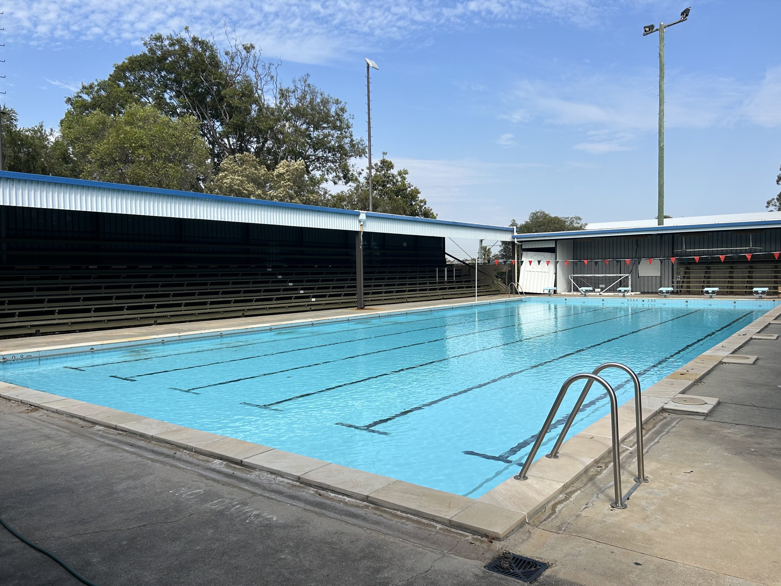 Outdoor lap pool with grandstand seating at a swim club
