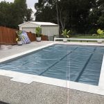 Blue Ultra Silverback solar pool cover installed over a backyard pool