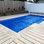 Ultra Premium Blue pool cover with roller mechanism beside a timber deck