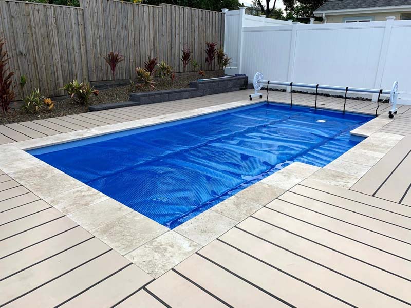Ultra Premium Blue pool cover with roller mechanism beside a timber deck