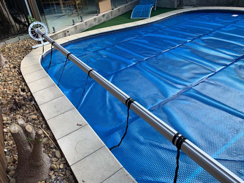 Roller bar extending the Ultra Premium Blue pool cover over the water