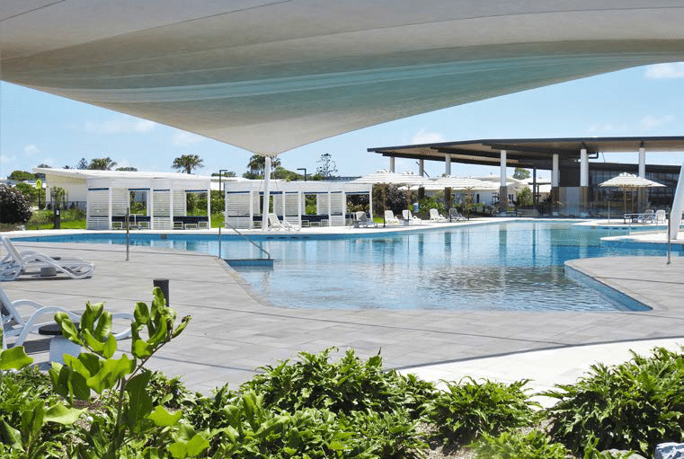 Resort swimming pool with white cabanas and a shade sail overhead