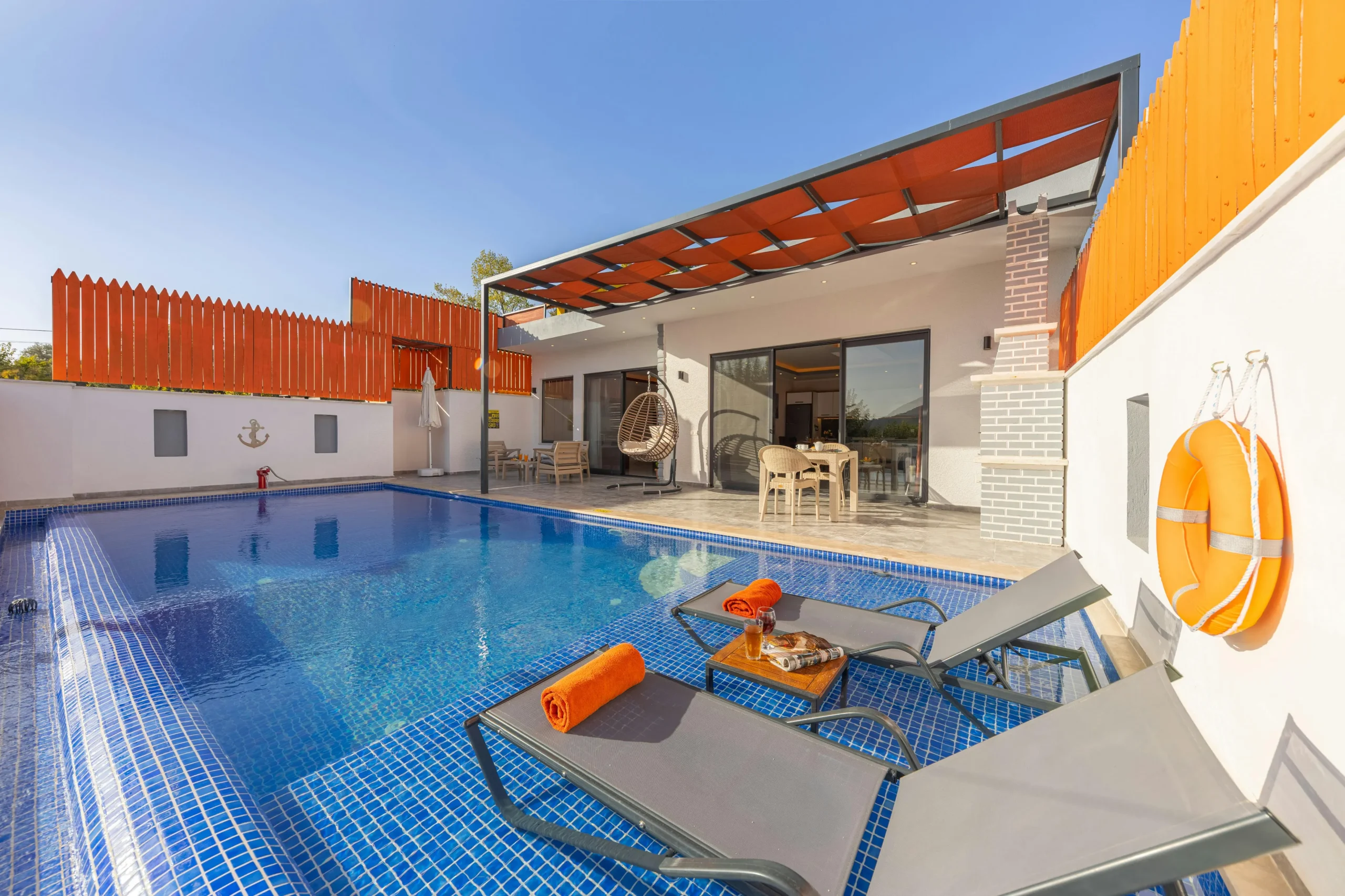 Stylish backyard swimming pool with sun loungers and orange fence, Pool Heat Pumps page hero