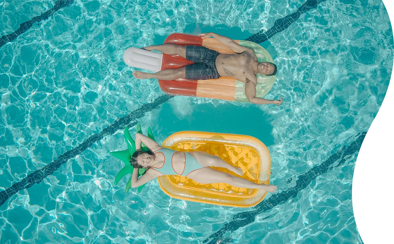 Aerial view of two people relaxing on inflatable pool floats in a lap pool