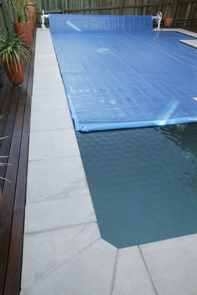 Ultra Thermal pool cover partially rolled back on a long lap pool
