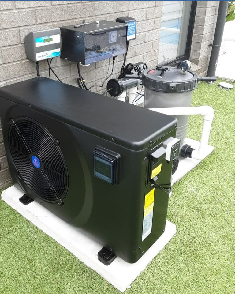 Black pool heat pump installed beside filtration and control equipment on turf
