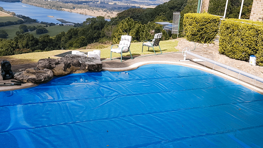 Blue solar pool cover on a pool overlooking a rural valley view
