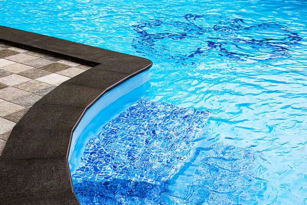 Close-up of pool corner steps with blue mosaic tile - Liquid Pool Cover Guide | Benefits, How It Works & Top Picks
