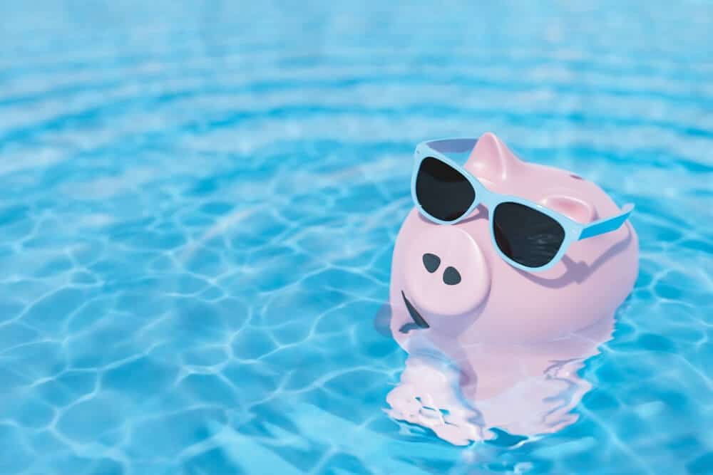 Pink piggy bank wearing sunglasses floating in a pool - How To Save Your Pool Costs? The Actionable Tips & FAQs