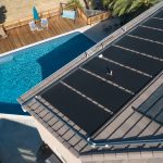 Aerial view of rooftop solar pool heating panels above a backyard pool