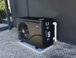 AES inverter pool heat pump installed on a concrete pad against an outdoor wall